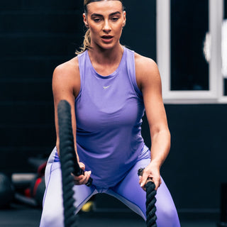 A woman lifting weights wearing a purple fade t shirt